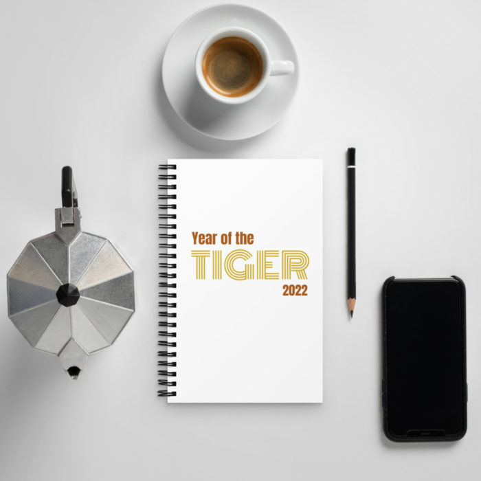 Photo layout of a percolator, a cup of coffee, a pencil, a black smart phone and in the middle a notebook with the "Year of the Tiger 2022" Notebook