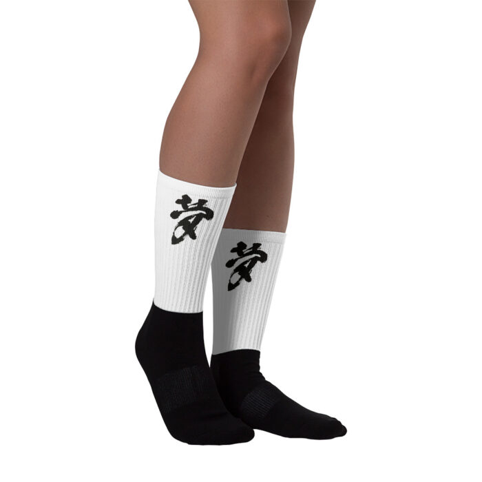 Black bottomed socks with a white top and the calligraphy "Dream" on it. The legs are bare up to the knees